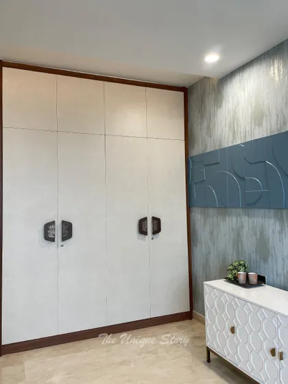 A full view of the custom wardrobe in the study room, featuring a textured finish and unique handles. The wardrobe is set against a wall with a concrete finish and a 3D art panel, adding an industrial-chic touch.