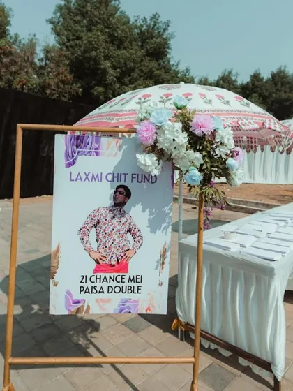 A quirky and fun welcome sign for a Carnival Fiesta. We love incorporating humor and pop culture references, like this "Laxmi Chit Fund" sign, to create a playful atmosphere.