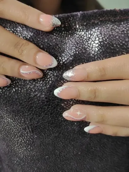 A close-up of the glitter French nails, showing the mix of fine glitter and a delicate hand-painted swirl.