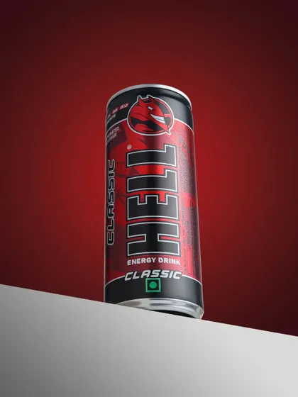 A commercial shot for Hell energy drink. The sharp lighting and bold red background are designed to match the brand's high energy identity.