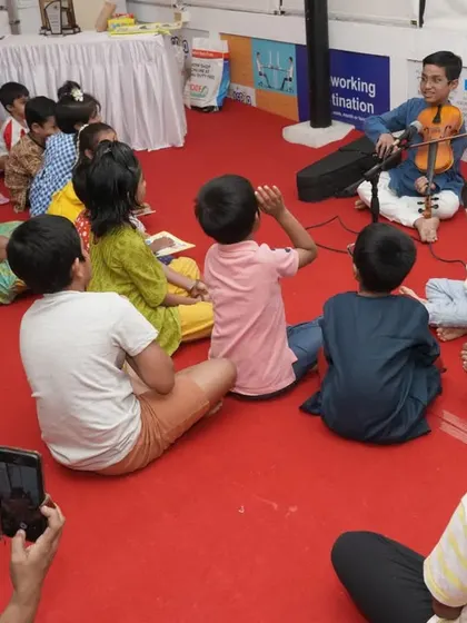 A young musician plays the violin for an attentive audience of children. Our book tours always feature live performances to bring the instruments from the book to life.
