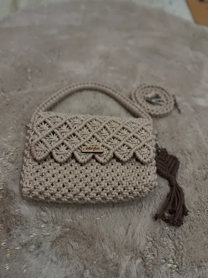 A lovely beige sling bag with a scalloped flap design, paired with a dark brown tassel. This was part of a recent delivery.