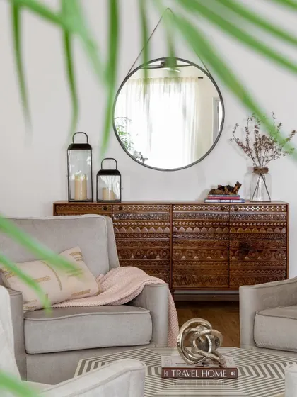 A carved wooden credenza provides beautiful storage in this living room. The intricate detail of the piece adds texture and a sense of craftsmanship to the space.