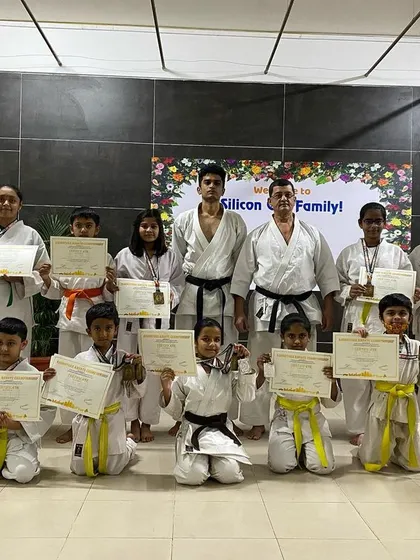 A proud display of achievement. Our students hold up their certificates and medals, a tangible result of their perseverance in karate training.