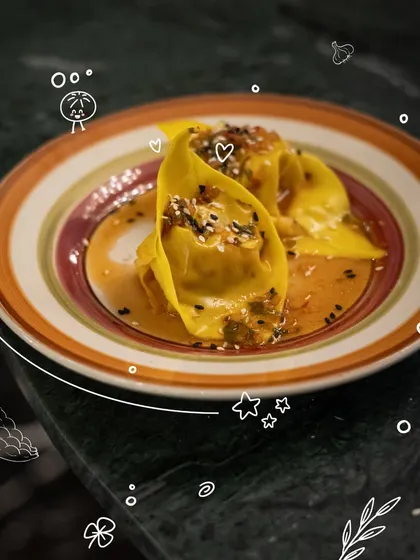 The final product: beautifully shaped tortelloni resting in a savory sauce, garnished with sesame seeds. This is a dish made and plated by a participant in our dim sum workshop.