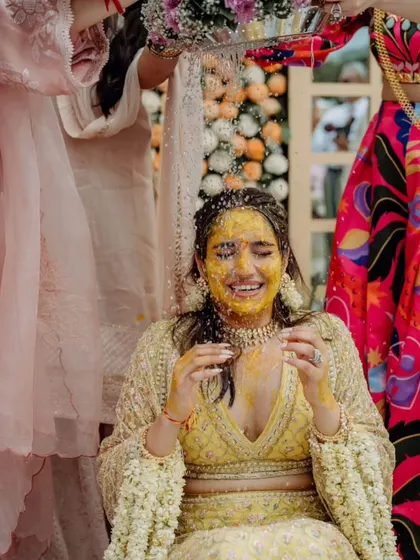 A moment of pure, unadulterated joy as the bride is showered with flower petals and water during her 'Mangal Snanam' ritual, a beautiful South Indian tradition we incorporated into her Haldi.