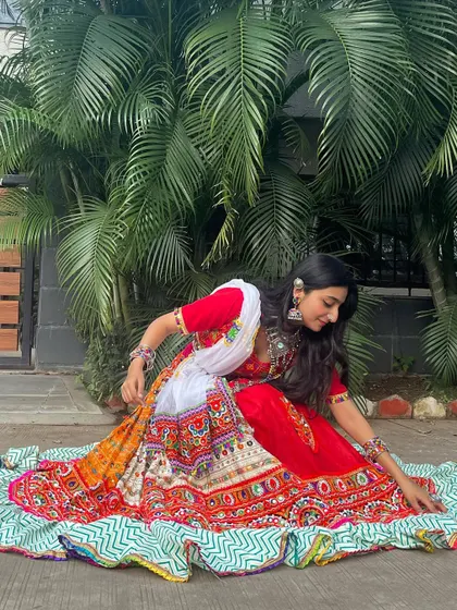 Another pose in the red and white outfit, showing the flow and design of the full lehenga skirt.