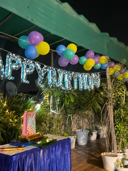 A simple yet beautiful rooftop birthday decoration. The setup includes a 'Happy Birthday' foil balloon banner and colorful balloon bunches to create a festive mood.