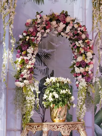 A beautiful floral arch in shades of pink, purple, and white, set against a hand-painted backdrop. This served as a lovely focal point within the larger decor scheme.