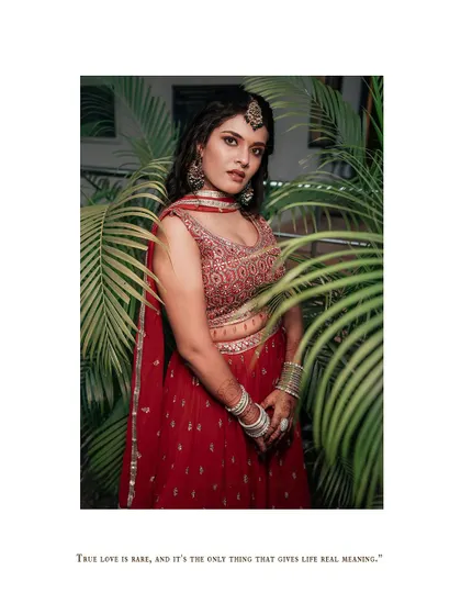 A full-length portrait of the bride in her red lehenga, surrounded by greenery.