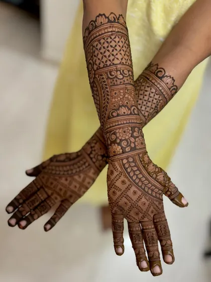 A crossed-hands view of the dense bridal mehendi.