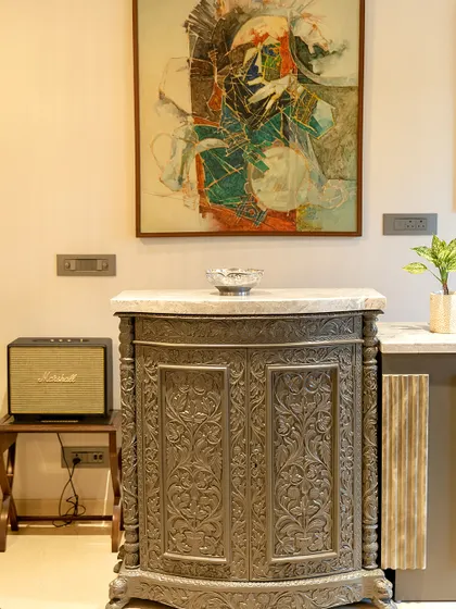 An intricately carved wooden cabinet serves as both a functional piece and a work of art. We paired it with a modern abstract painting, creating a beautiful dialogue between traditional craft and contemporary art.