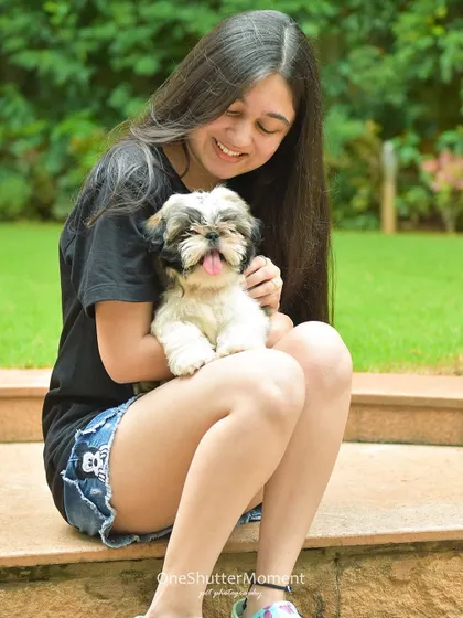 A girl and her adorable Shih Tzu puppy sharing a sweet moment. The puppy's little pink tongue and happy expression are just priceless.