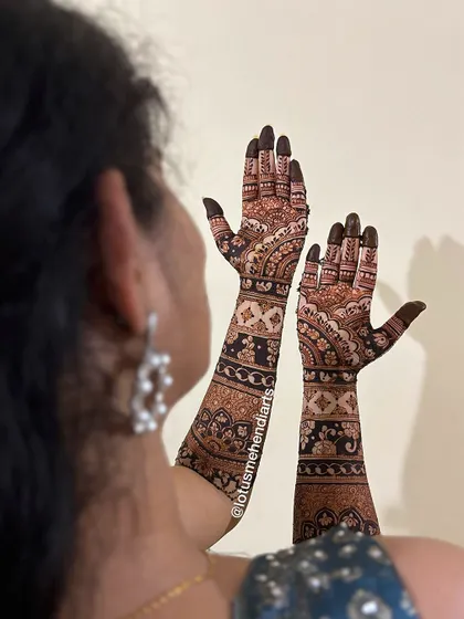 A bride admiring her intricate bridal mehendi, a design rich with traditional patterns and floral motifs.