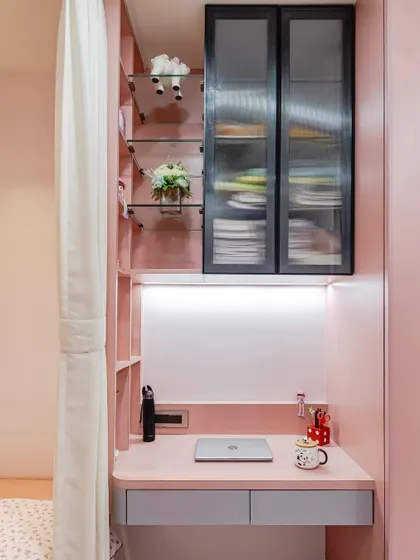 A close-up of the built-in study desk. The design features under-cabinet lighting to illuminate the workspace, a sleek grey drawer, and fluted glass on the upper cabinets to stylishly conceal clutter.