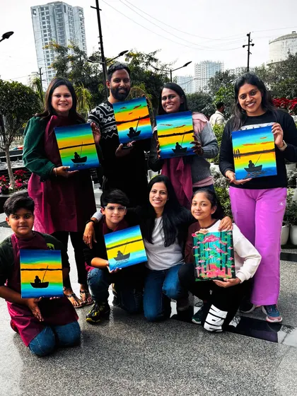 A final group shot from a sunny outdoor workshop, with everyone holding their beautiful sunset and forest paintings.