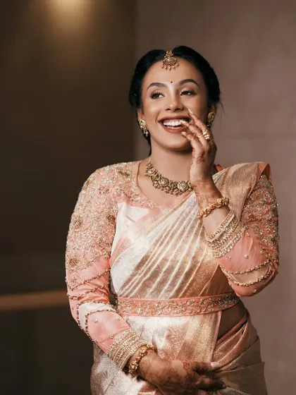 A joyful, candid shot of the bride. Her smile is as radiant as the intricate work on her beautiful blouse.