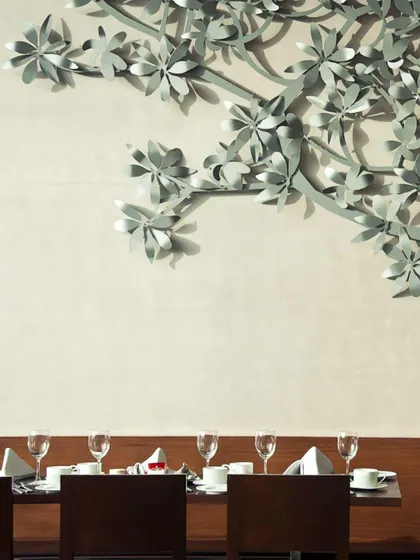 A close-up of a custom metal art installation, shaped like a flowering branch. This detail adds a layer of delicate craftsmanship to the dining area's interior design.