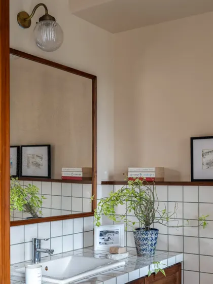 A simple and elegant bathroom in Calcutta. The space uses classic white subway tiles, a wood-framed mirror, and a touch of greenery to create a timeless and calming atmosphere.