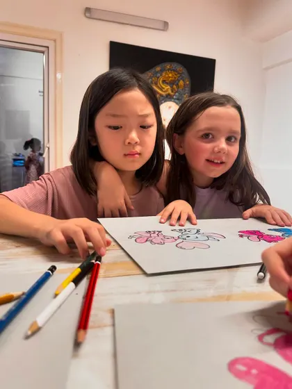 Two friends share a moment while working on their character drawings. Art class is a great place to bond and make new friends.