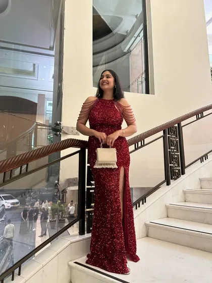 Posing on the staircase at a wedding reception. This red gown is a perfect example of a wedding guest outfit that is show-stopping yet elegant, without upstaging the bride.