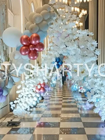 An immersive entrance for a Frozen party, featuring a walkway lined with faux snow-covered trees and balloon arches in icy colors.