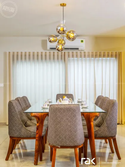 A beautifully designed dining room where light and dark shades mix perfectly. The glass-top table with a wooden base and the modern chandelier amplify the elegance of the space.