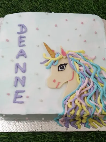 A magical unicorn cake with a flowing, multi-colored buttercream mane. The design is simple yet enchanting, perfect for a unicorn lover.