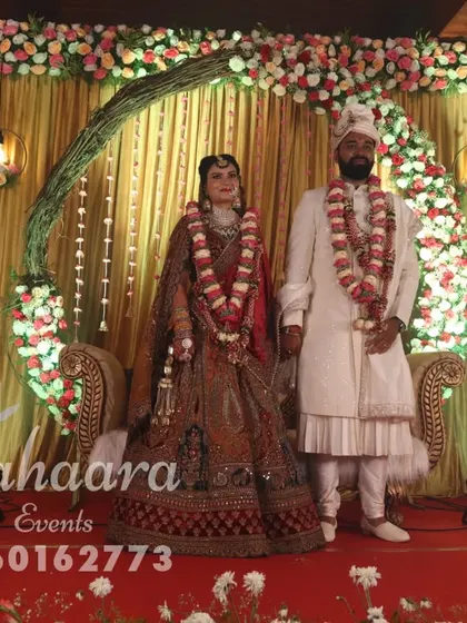 A couple poses on their beautiful reception stage. We work to create the perfect backdrop that not only looks great in person but also makes for stunning wedding photography.