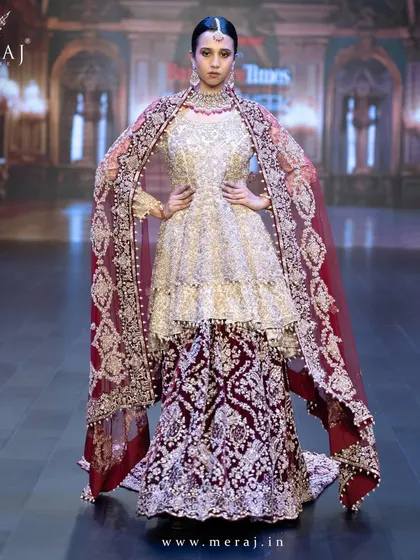 A powerful stance in the Gold and Maroon Indo-Western ensemble, with its velvet tail lehenga and net double-layer peplum top.