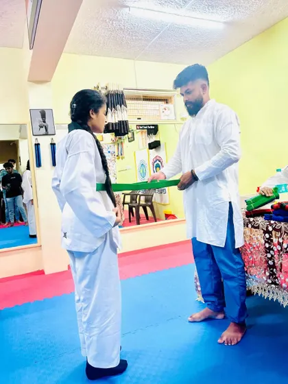 A student receives her new green belt, a sign of her growing skills and commitment.