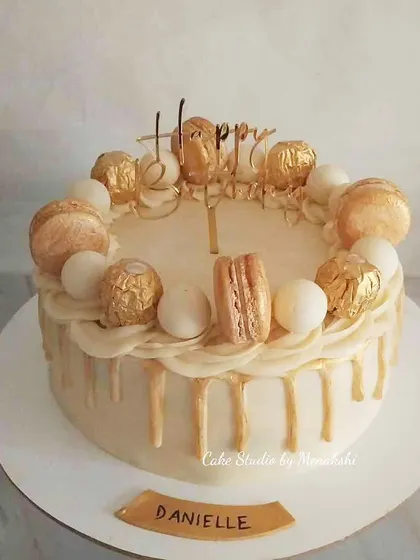 A classic white and gold drip cake that exudes luxury. This no-fondant design is adorned with golden macarons and Ferrero Rocher, making it a perfect centerpiece for a sophisticated party.