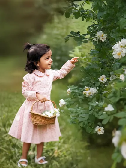 A moment of quiet curiosity. This toddler stops to inspect the flowers in the garden, a simple, beautiful moment of a child discovering the world around her.
