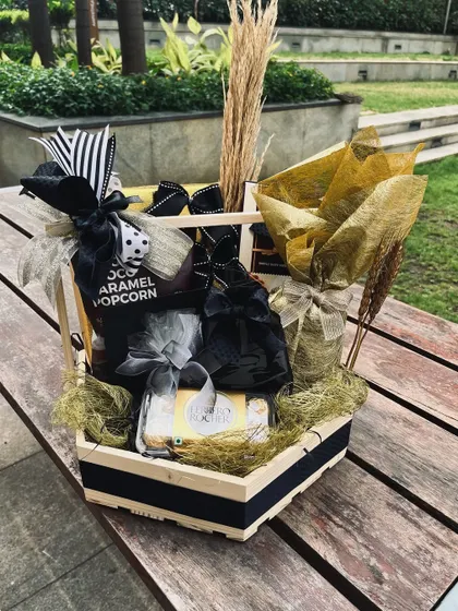 A black, white, and gold themed hamper that showcases a bold and modern styling approach, using contrasting ribbons and metallic accents.
