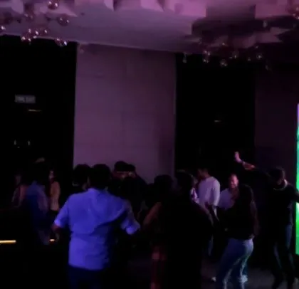 A corporate crowd dancing in front of a custom LED visual display.