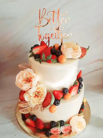 A stunning rustic anniversary cake that celebrates being better together. This two-tier, no-fondant cake is generously decorated with fresh berries and flowers for a natural and beautiful look.