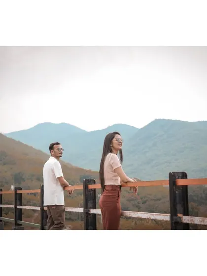 A couple enjoys a scenic mountain view from a lookout point during their casual and relaxed pre-wedding photoshoot.