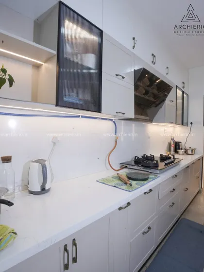 A classic white kitchen with shaker-style cabinets, a white quartz countertop, and elegant handles, creating a timeless and clean look.
