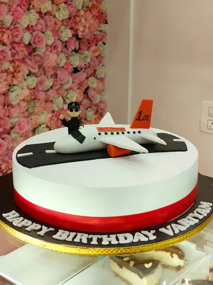 This aeroplane cake features a pilot sitting on the plane on a runway. It's a fun and personalized cake for a first birthday.