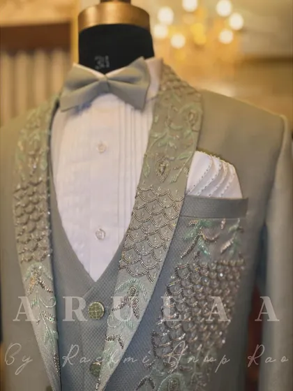 The full three-piece sage green suit on display. The detailed embroidery on the lapel and pocket makes this a standout piece, perfect for a groom who wants something different.