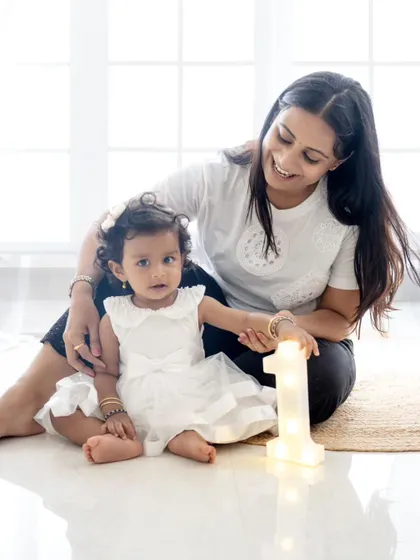 A sweet moment between mother and daughter next to a light-up "1" prop. Celebrating the first year is a milestone for parents too!