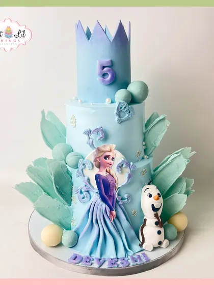 A grand Frozen-themed cake for a 5th birthday. This multi-tiered creation features Elsa, Olaf, and a magnificent ice-blue crown, decorated with sugar icicles and snowflakes.
