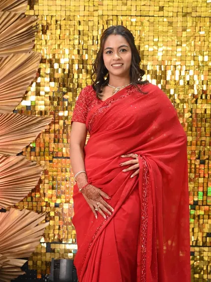 A full shot of the bridesmaid in her red saree against a gold backdrop. She looks absolutely radiant.