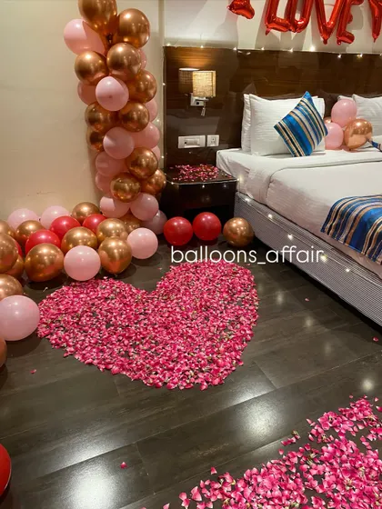 A close-up of the floor decor, where a heart made of rose petals is surrounded by rose gold, pink, and red balloons.