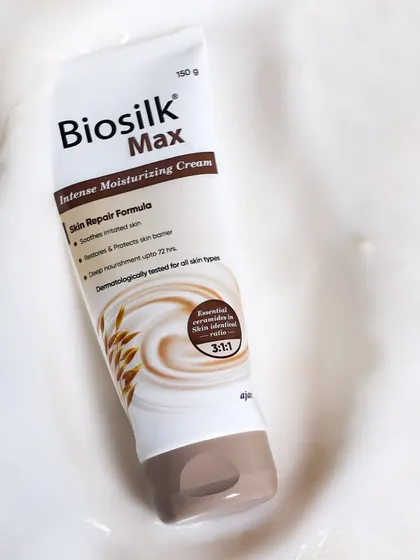 An abstract and textural shot, with the moisturizing cream tube nestled in a swirl of white lotion. This focuses on the product's rich, creamy texture and intense moisturizing formula.