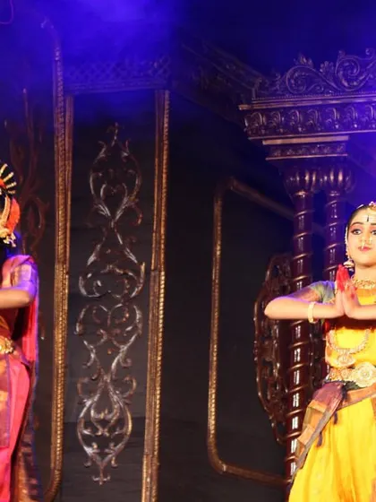 Two of our dancers in a moment of quiet devotion during the "Nava Durga" performance. The intricate details of their costumes and the grand stage set are visible here.