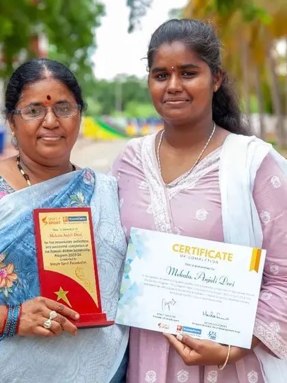 A graduate of the Female Athlete Leadership Programme poses with her mother, holding her certificate and award. This image captures the pride and shared success that our programs aim to foster within families and communities.