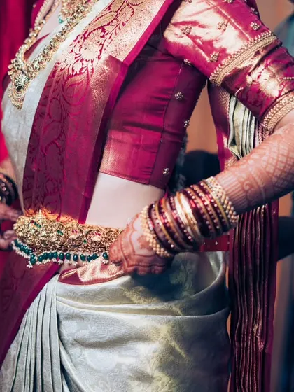 A detailed shot of the bride adjusting her intricate gold waist belt, highlighting the craftsmanship of her bridal jewelry.