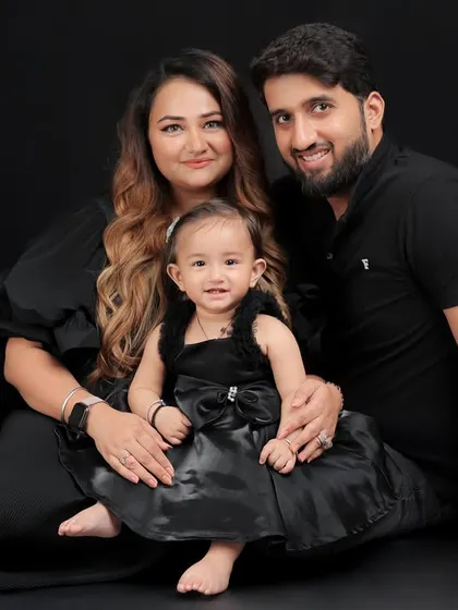 A classic family portrait. Posed against a simple black background, the focus is entirely on the love and connection between this beautiful family of three.