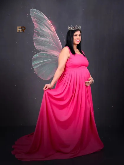 A fairytale moment. The mom-to-be looks like a princess in her pink gown, complete with a crown and magical butterfly wings.